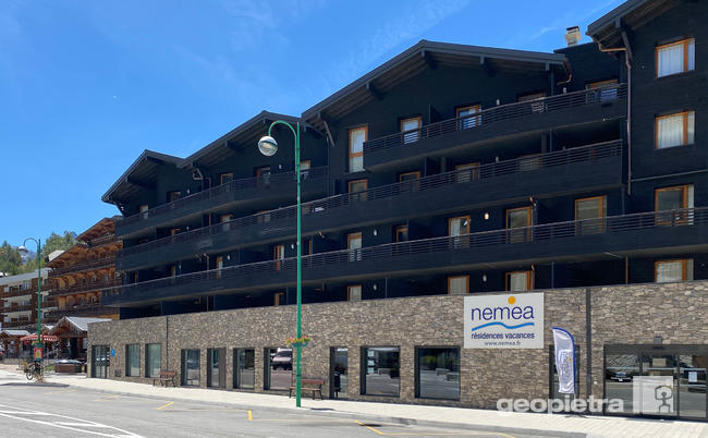 Nemea residential complex in the French Alps with Geopietra manufactured stone cladding on the ground floor, dark wooden facade and balconies.